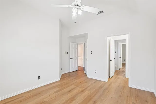 an empty room with wooden floor and ceiling fan