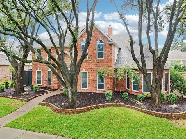 a front view of a house with a yard and an tree