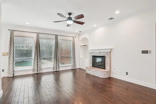 an empty room with wooden floor fireplace and windows