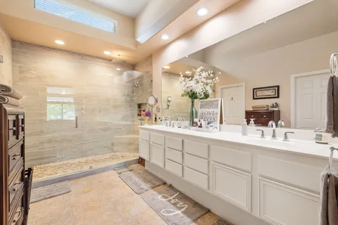 a large bathroom with a double vanity sink a large mirror a bathtub and shower