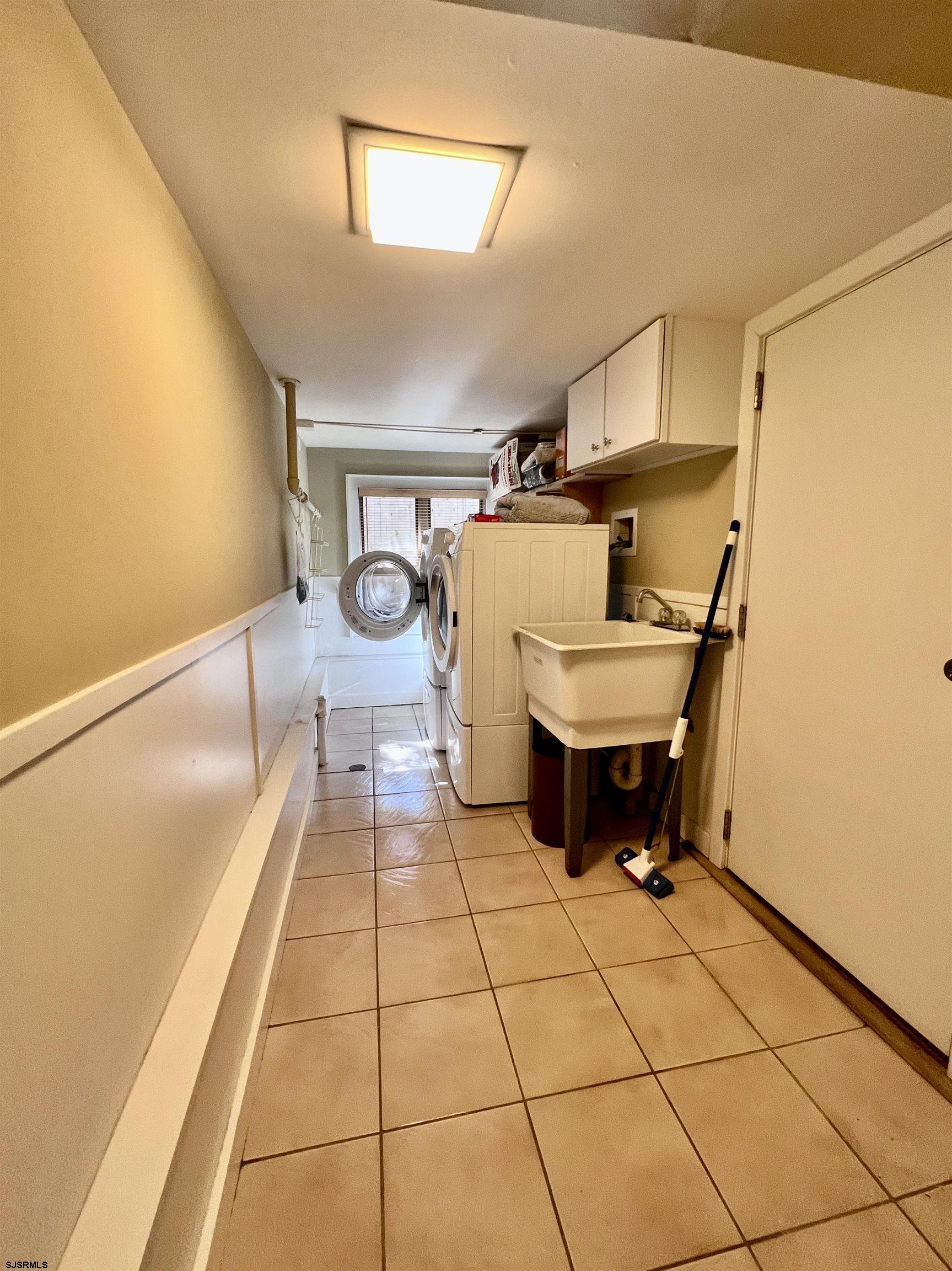 7 North Delavan Avenue, Unit MEMORIAL DAY LABOR DAY Margate City, NJ 08402 - Photo 13 of 60 a room with a washing machine and cabinets