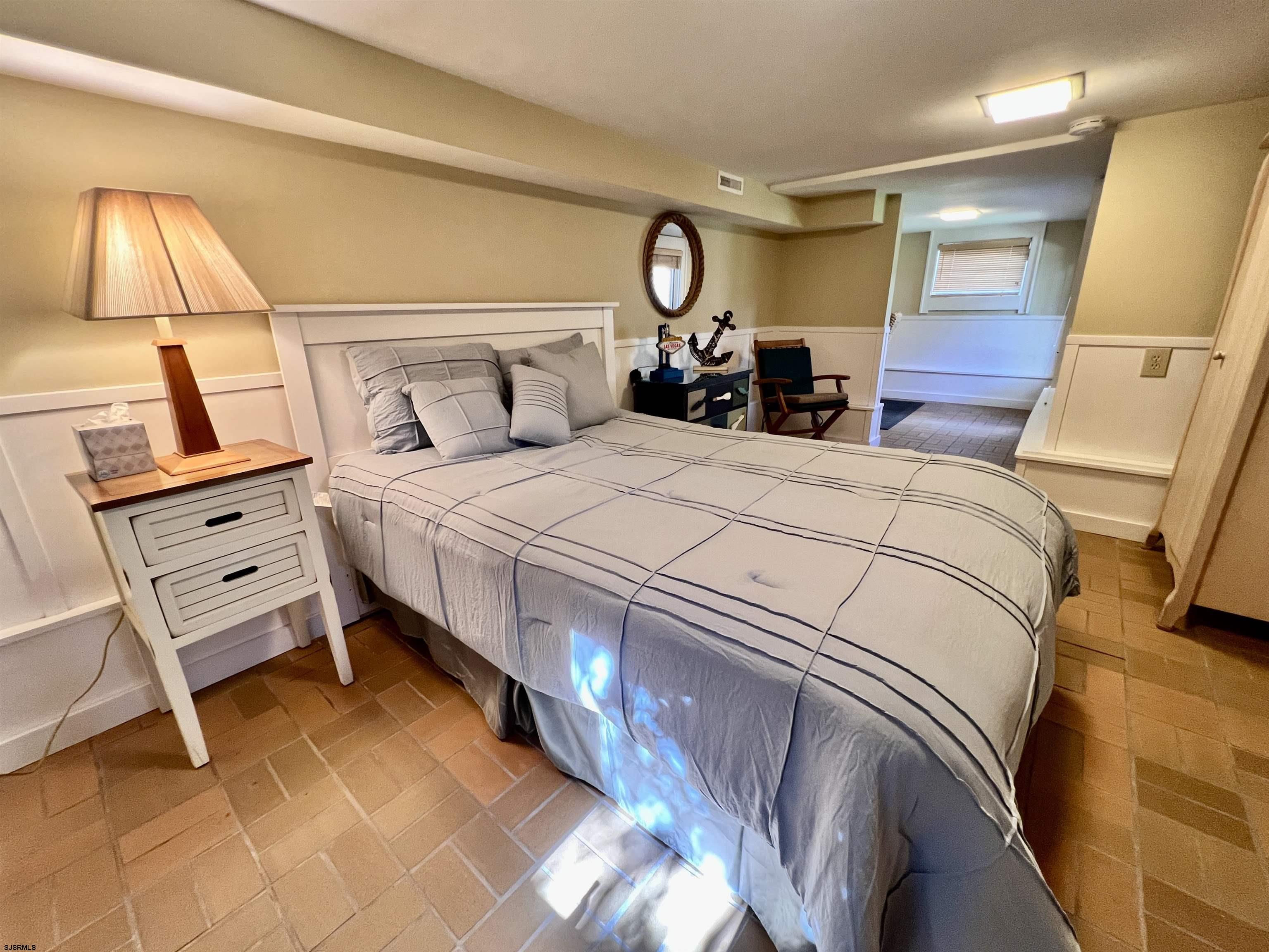 7 North Delavan Avenue, Unit MEMORIAL DAY LABOR DAY Margate City, NJ 08402 - Photo 17 of 60 a bedroom with a bed and a lamp on dresser