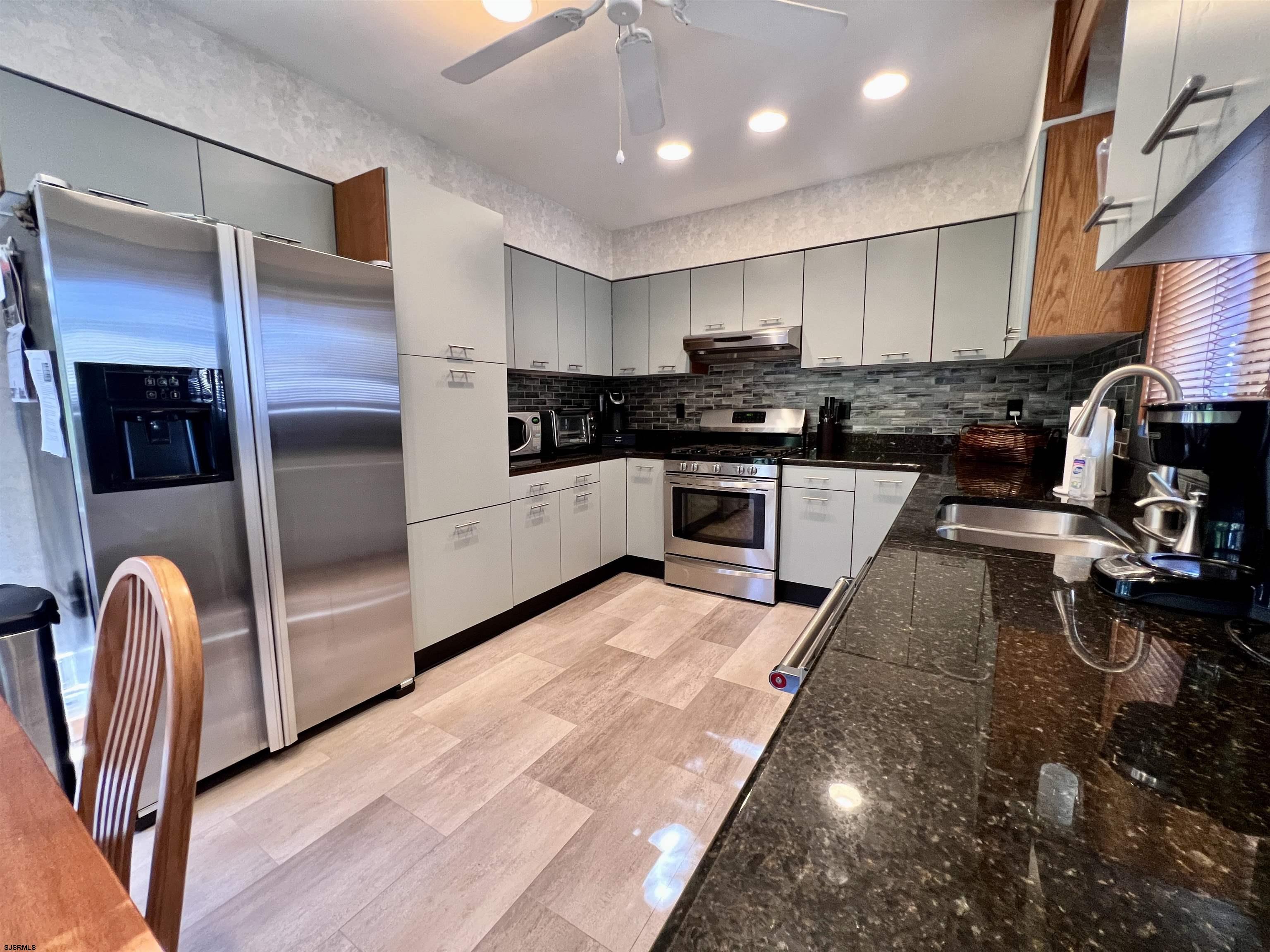7 North Delavan Avenue, Unit MEMORIAL DAY LABOR DAY Margate City, NJ 08402 - Photo 28 of 60 a kitchen with stainless steel appliances granite countertop a refrigerator a stove top oven a sink and dishwasher