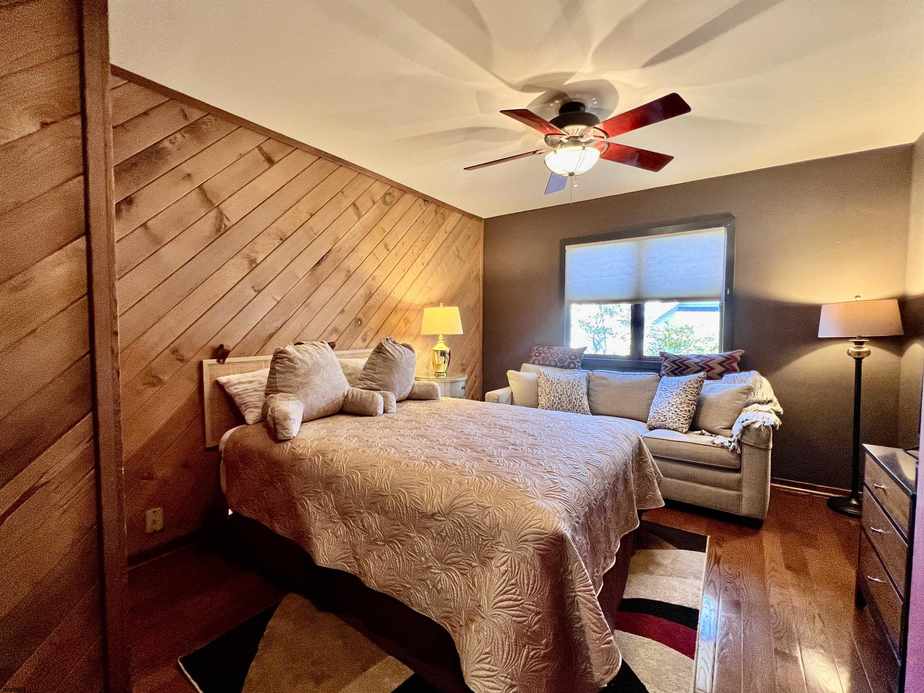 7 North Delavan Avenue, Unit MEMORIAL DAY LABOR DAY Margate City, NJ 08402 - Photo 33 of 60 a bedroom with a bed chandelier and a large window