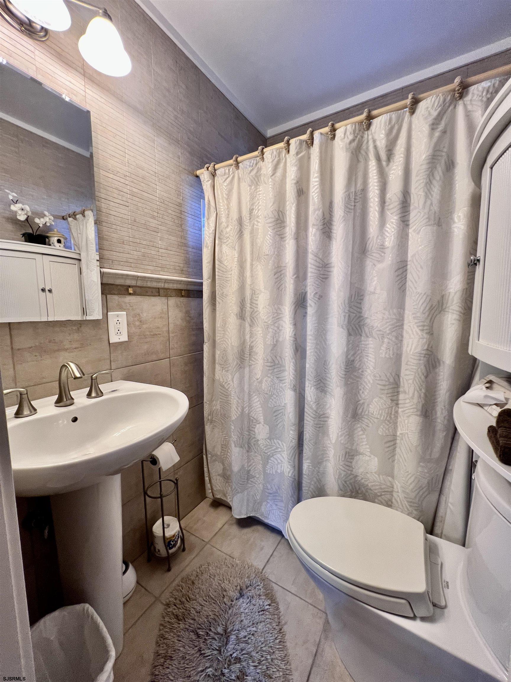 7 North Delavan Avenue, Unit MEMORIAL DAY LABOR DAY Margate City, NJ 08402 - Photo 35 of 60 a bathroom with a toilet a sink and a mirror