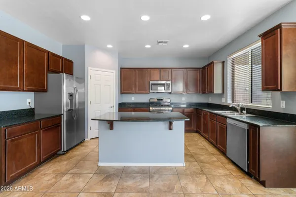 a large kitchen with stainless steel appliances granite countertop a large counter top cabinets and a sink