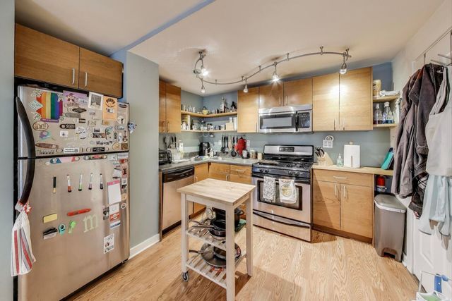 a kitchen with stainless steel appliances a refrigerator and a wooden floor