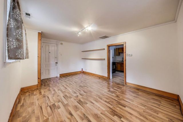 a view of empty room with wooden floor and fan