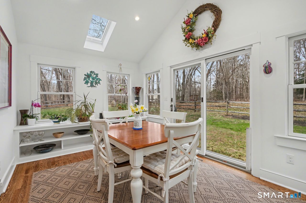 61 Bishop Lane Madison, CT 06443 - Photo 18 of 41 a dining room with wooden floor a chandelier a wooden table and chairs