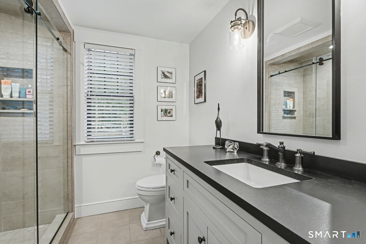 61 Bishop Lane Madison, CT 06443 - Photo 23 of 41 a bathroom with a granite countertop sink toilet a mirror and shower
