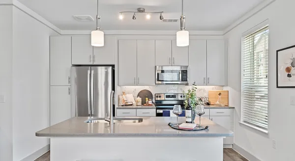 a kitchen with kitchen island granite countertop a sink a counter space appliances and cabinets
