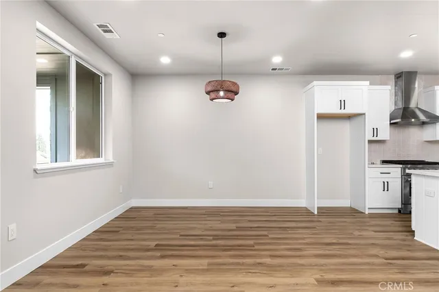 a view of empty room with wooden floor and window