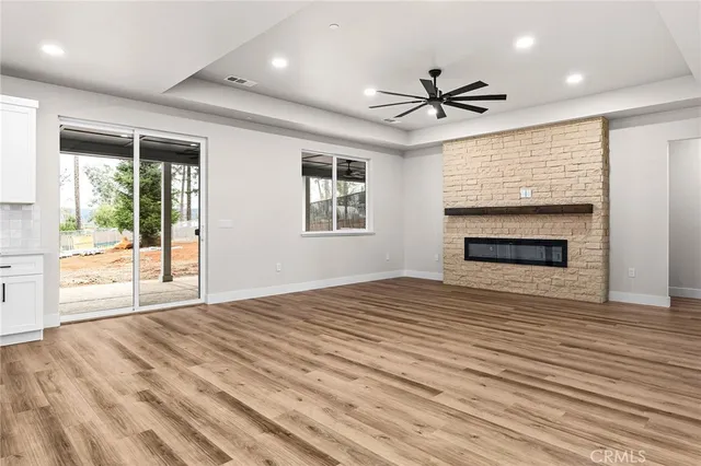 an empty room with wooden floor a ceiling fan and windows