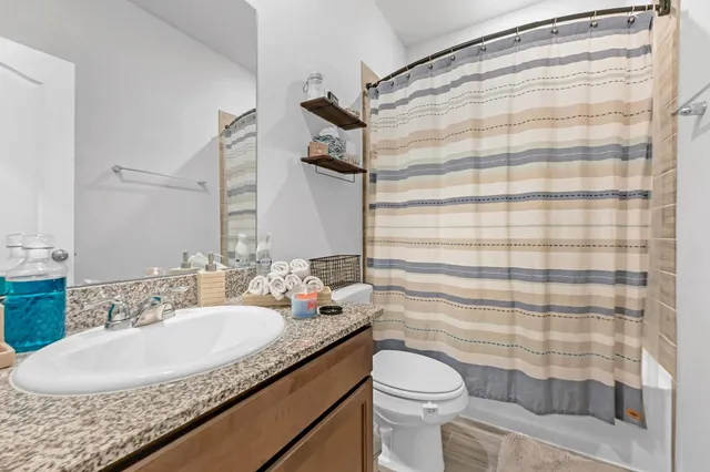 a bathroom with a granite countertop sink a toilet and shower