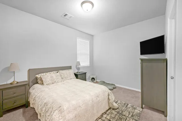 a bedroom with a bed and a flat tv screen on the dresser