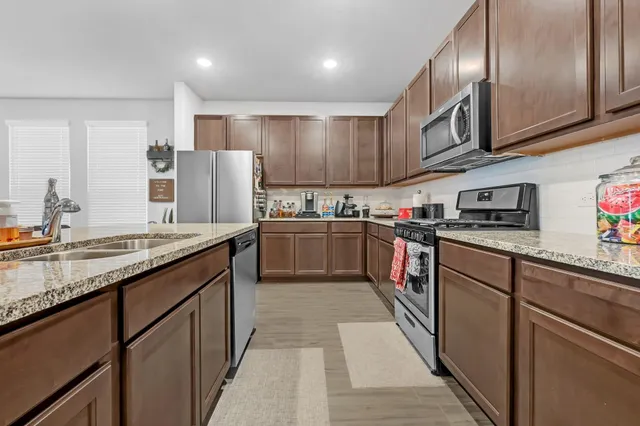 a kitchen with stainless steel appliances granite countertop a sink stove and refrigerator