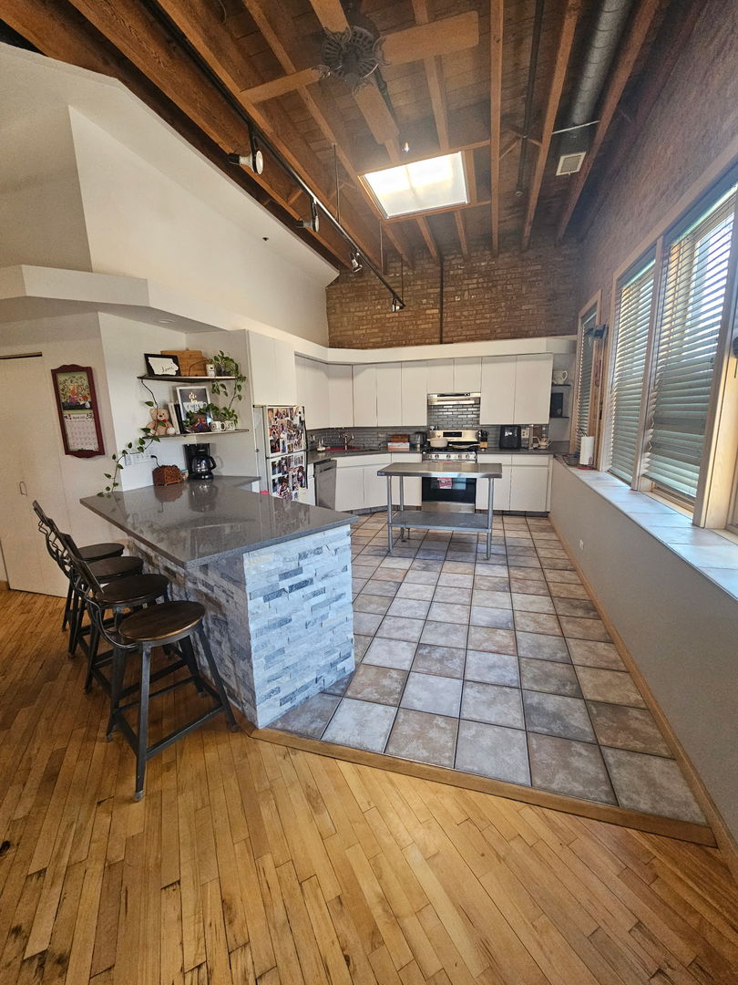 537 Custer Avenue, Unit 5 Evanston, IL 60202 - Photo 4 of 19 a kitchen with stainless steel appliances granite countertop a stove a sink dishwasher and cabinets with wooden floor