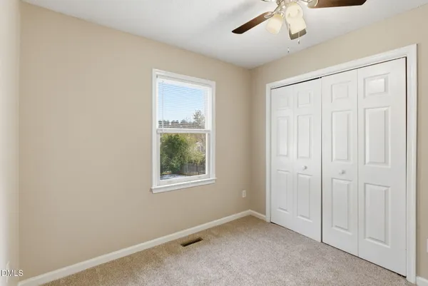 an empty room with windows and fan