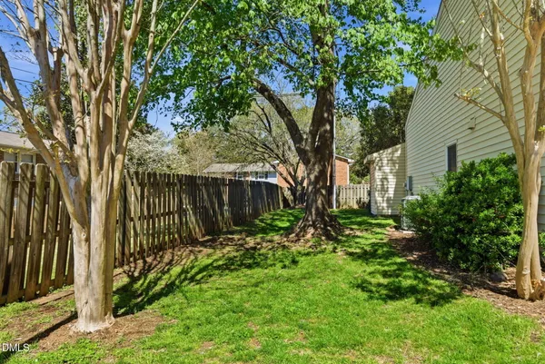 a view of a backyard with large trees and wooden fence