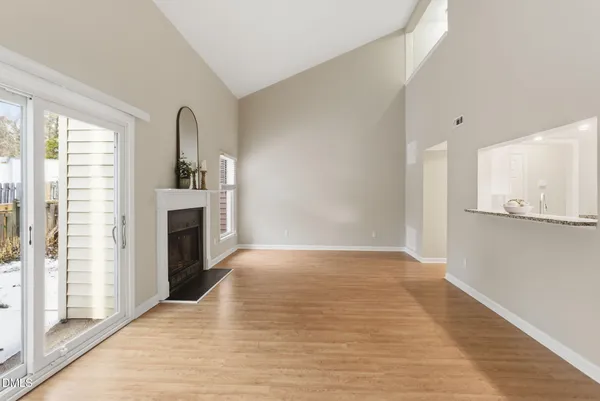 a view of empty room with kitchen and fireplace