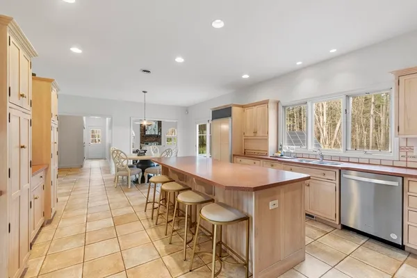 a dining hall with stainless steel appliances granite countertop a stove a sink a dining table and chairs