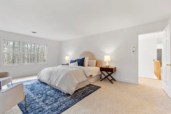 a bedroom with a large bed a rug and windows