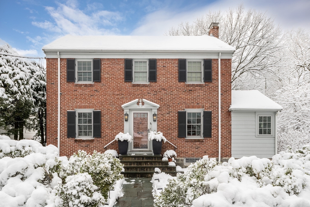 a front view of a house with a yard covered with snow