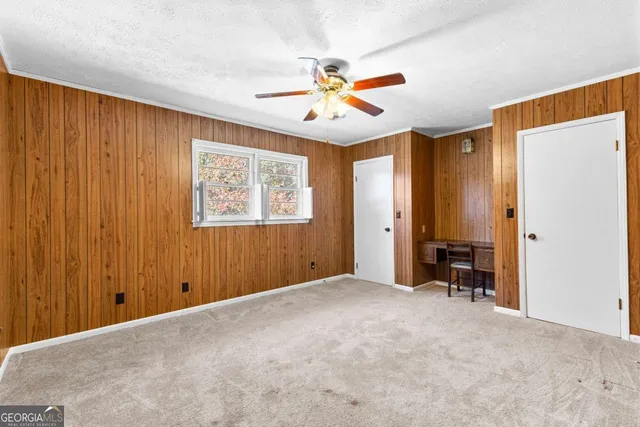 an empty room with windows and fan