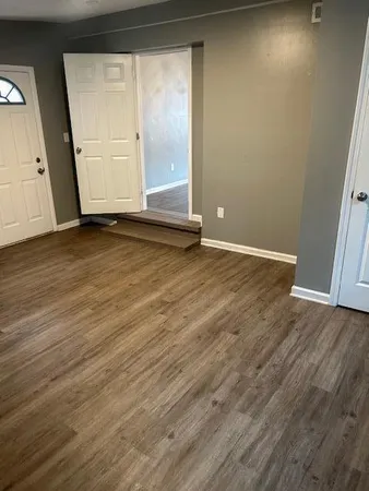 an empty room with wooden floor and windows
