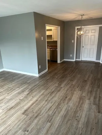 an empty room with wooden floor cabinet and windows