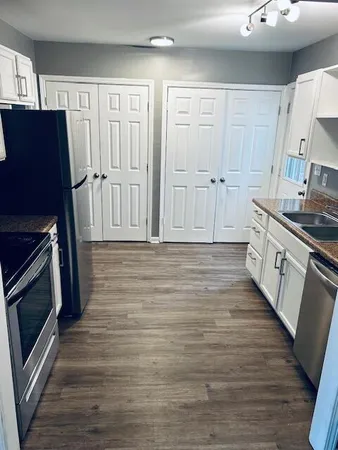 a kitchen with stainless steel appliances wooden floor and a refrigerator
