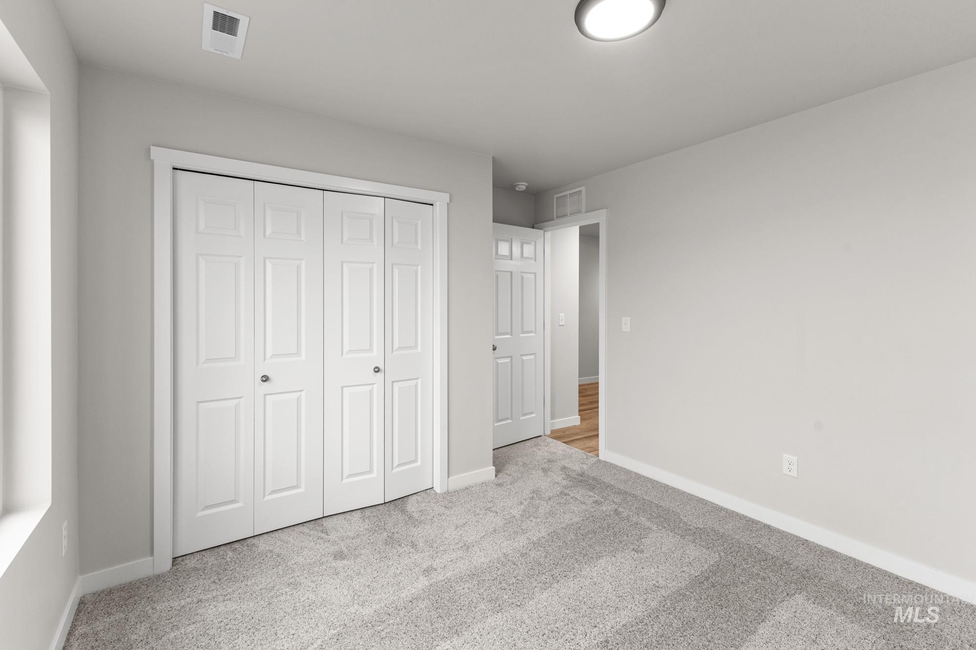 13307 Bank Street Caldwell, ID 83607 - Photo 15 of 20 Light gray carpet flooring, white bi-fold closet doors, white trim, recessed lighting, and a white paneled door