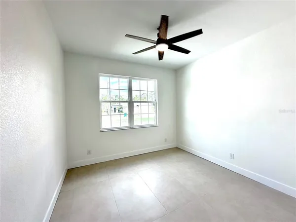 an empty room with ceiling fan and windows