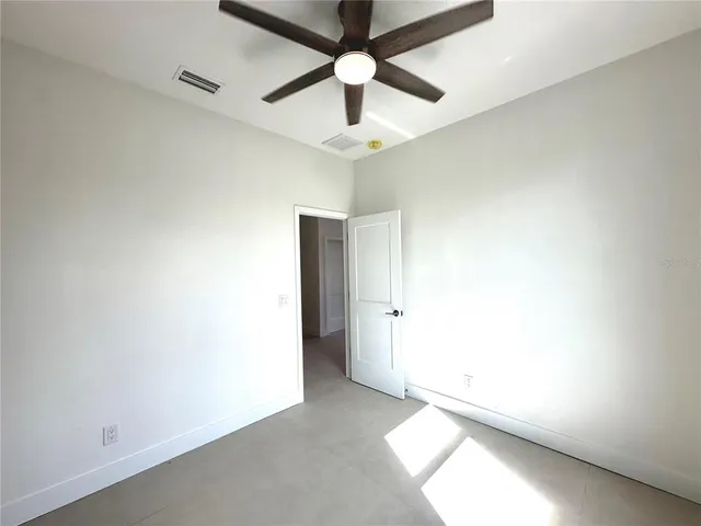 an empty room with a chandelier fan and a ceiling fan