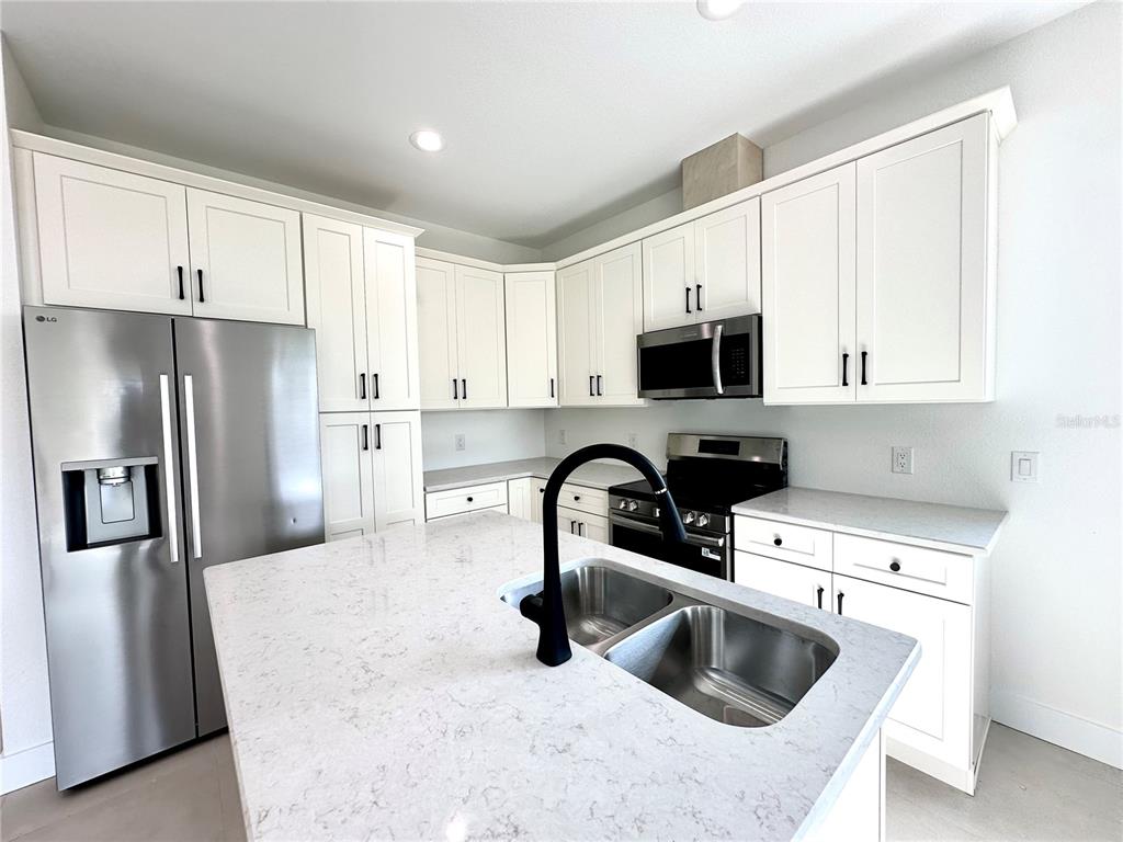 26129 Northern Cross Road Punta Gorda, FL 33983 - Photo 38 of 40 a kitchen with stainless steel appliances a sink a microwave a refrigerator and grey cabinets