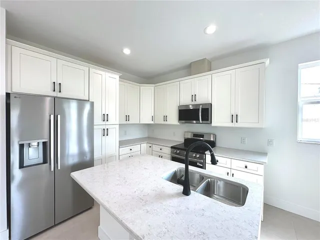 a kitchen with stainless steel appliances granite countertop a sink a stove a refrigerator a counter top space and cabinets