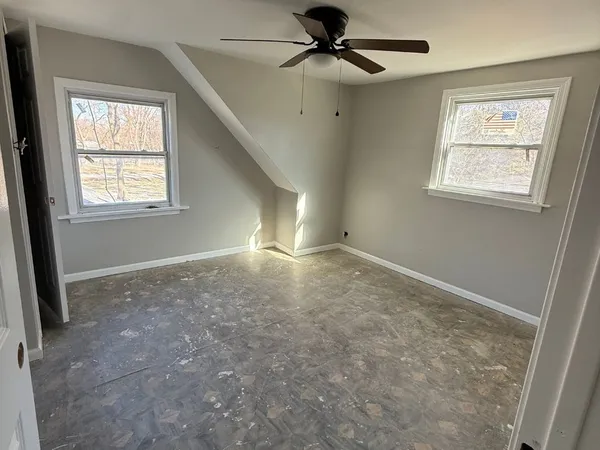 an empty room with windows and fan