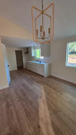 an empty room with wooden floor fan and windows