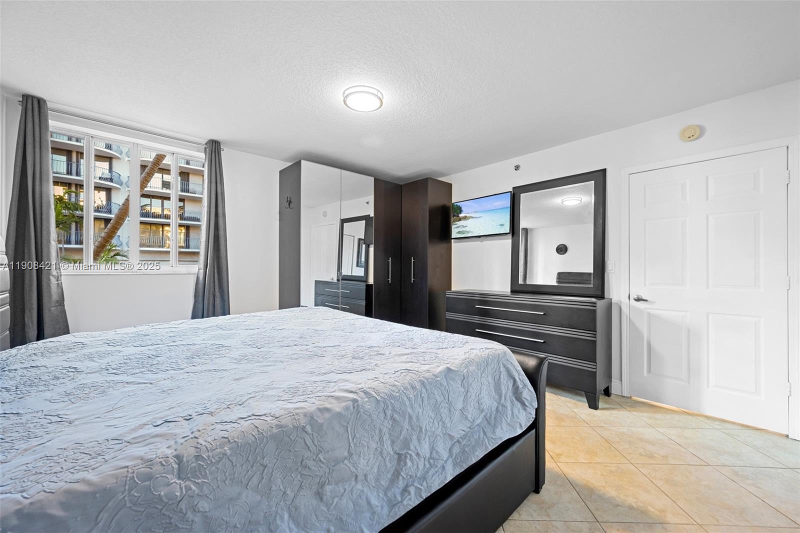 8888 Collins Avenue, Unit 105 Surfside, FL 33154 - Photo 14 of 29 a bedroom with a bed and a dresser