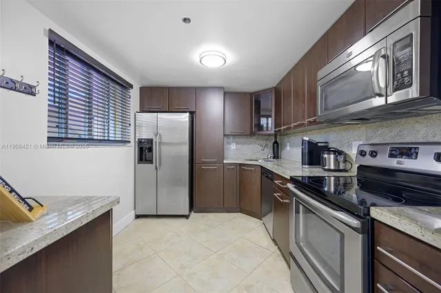 a kitchen with stainless steel appliances granite countertop a refrigerator a stove and a sink