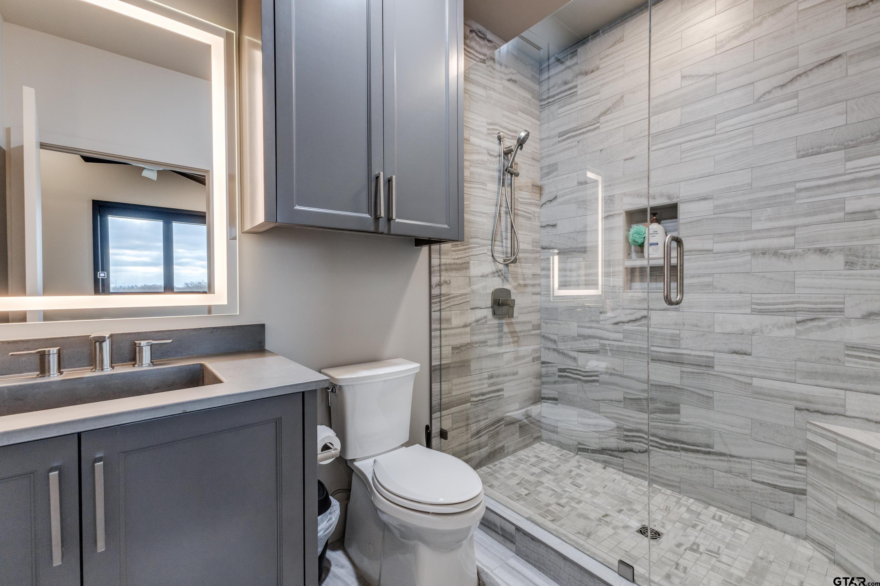 900 West Fm Saltillo, TX 75478 - Photo 18 of 36 a bathroom with a granite countertop toilet a sink a mirror and shower