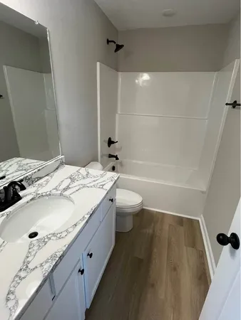 a bathroom with a granite countertop sink a toilet and shower