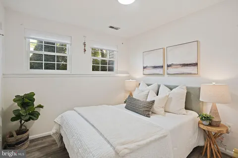 a bedroom with a bed potted plant with the wooden floor