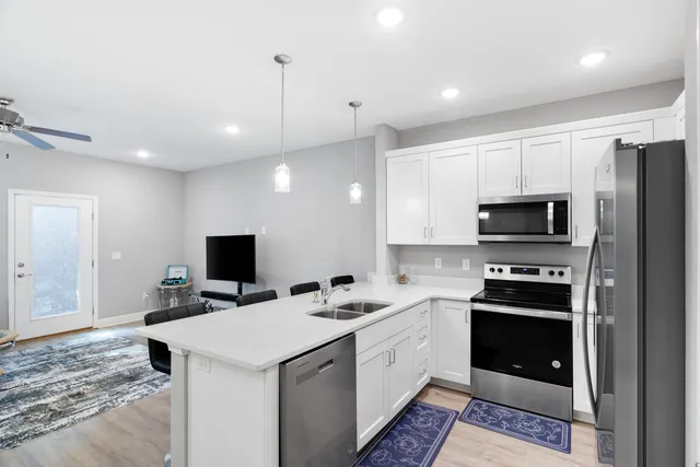 a kitchen that has a sink a microwave oven a refrigerator and cabinets