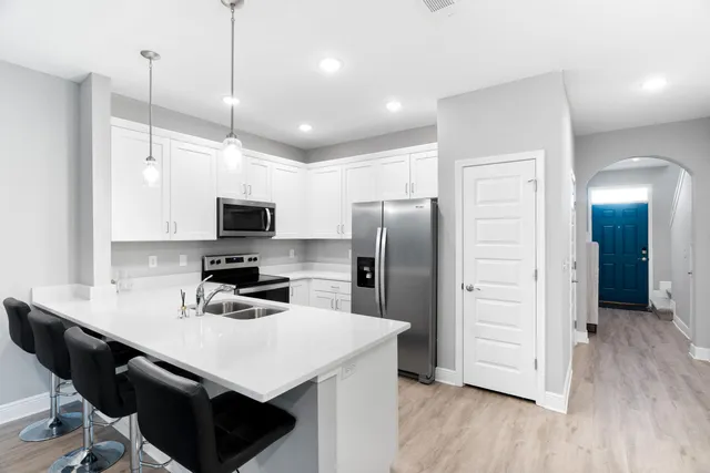 a kitchen with a refrigerator a sink and wooden floor