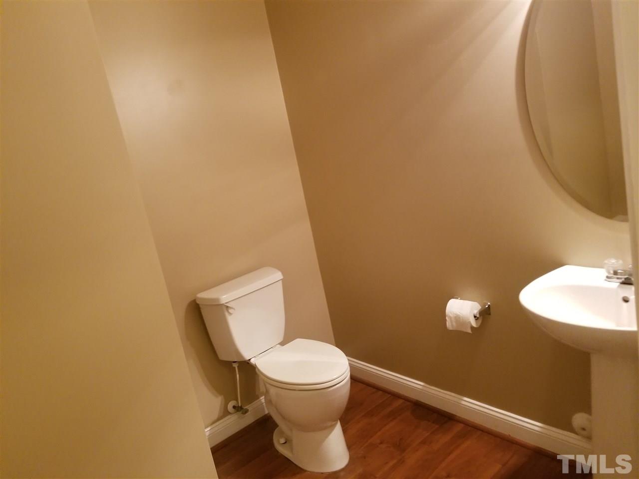 6044 Ricker Road Raleigh, NC 27610 - Photo 14 of 14 a white toilet sitting next to a white sink and vanity