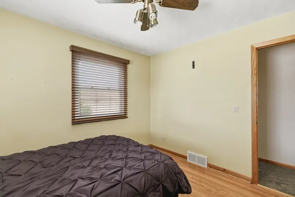 an empty room with wooden floor a ceiling fan and windows