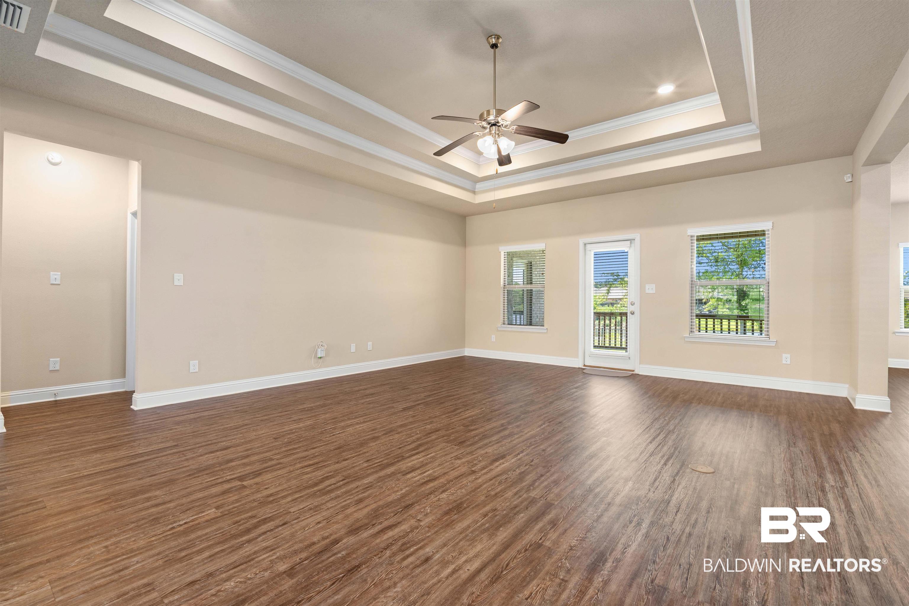 1864 Gwin Court Mobile, AL 36695 - Photo 8 of 37 Unfurnished living room featuring ceiling fan, crown molding, a tray ceiling, and dark hardwood / wood-style floors