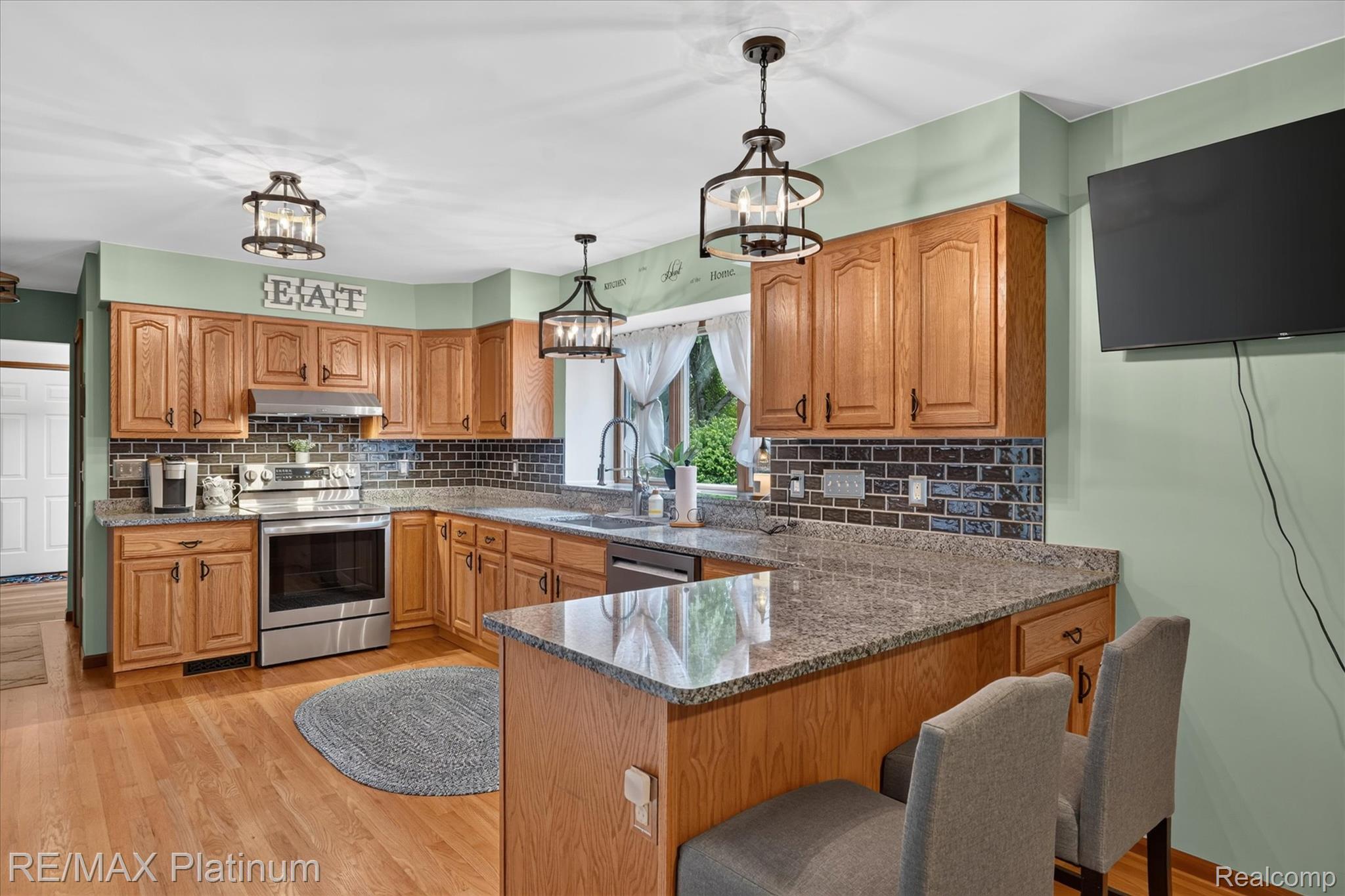 4457 Bradley Road Gregory, MI 48137 - Photo 12 of 79 Kitchen featuring wood cabinetry, granite-finish countertops, subway tile backsplash, stainless steel appliances, and wood-finish flooring