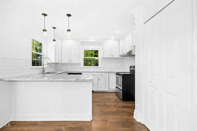 a kitchen with stainless steel appliances granite countertop a sink a stove a refrigerator a microwave oven with white cabinets